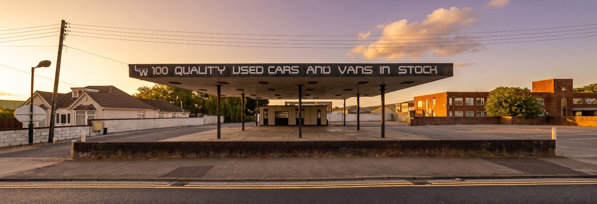 The former petrol filling station canopy at 352 Bristol Road, Bridgwater, at golden hour, signed 100 quality used cars and vans in stock